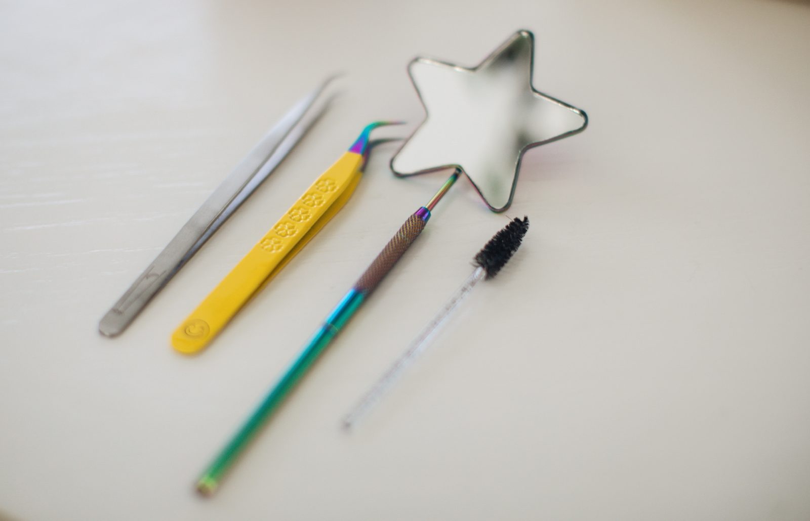 Isolation tweezers, volume tweezers, a spoolie and a star dish laid out